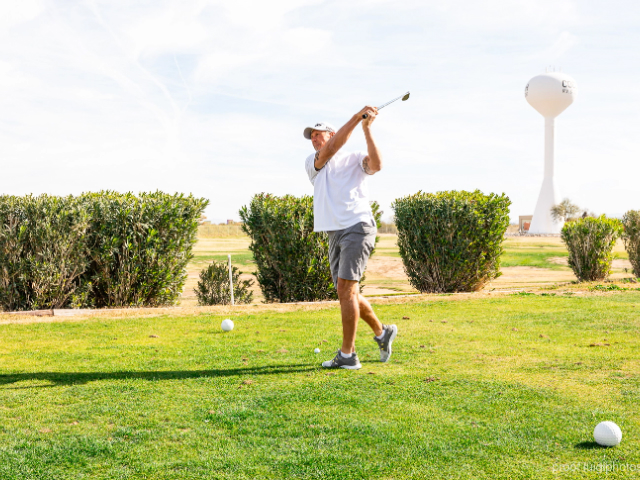 A golfer teeing off with the resort water tower in the background.